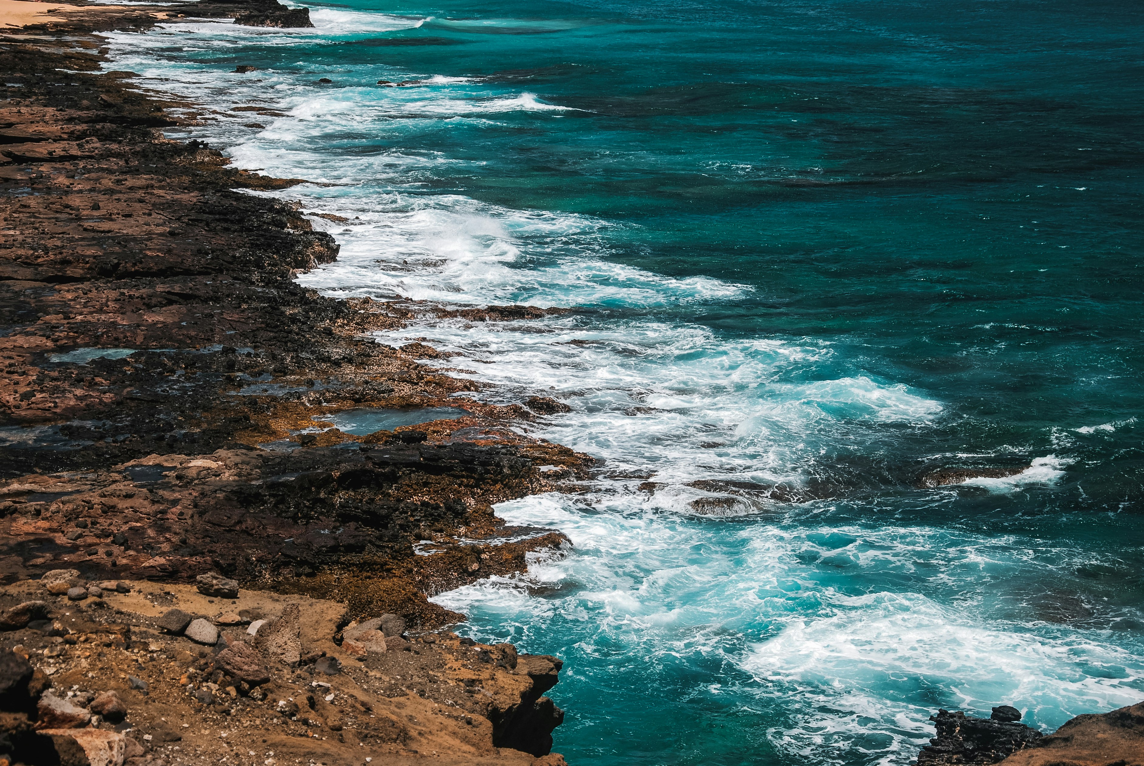 brown rocky shore with blue sea water during daytime